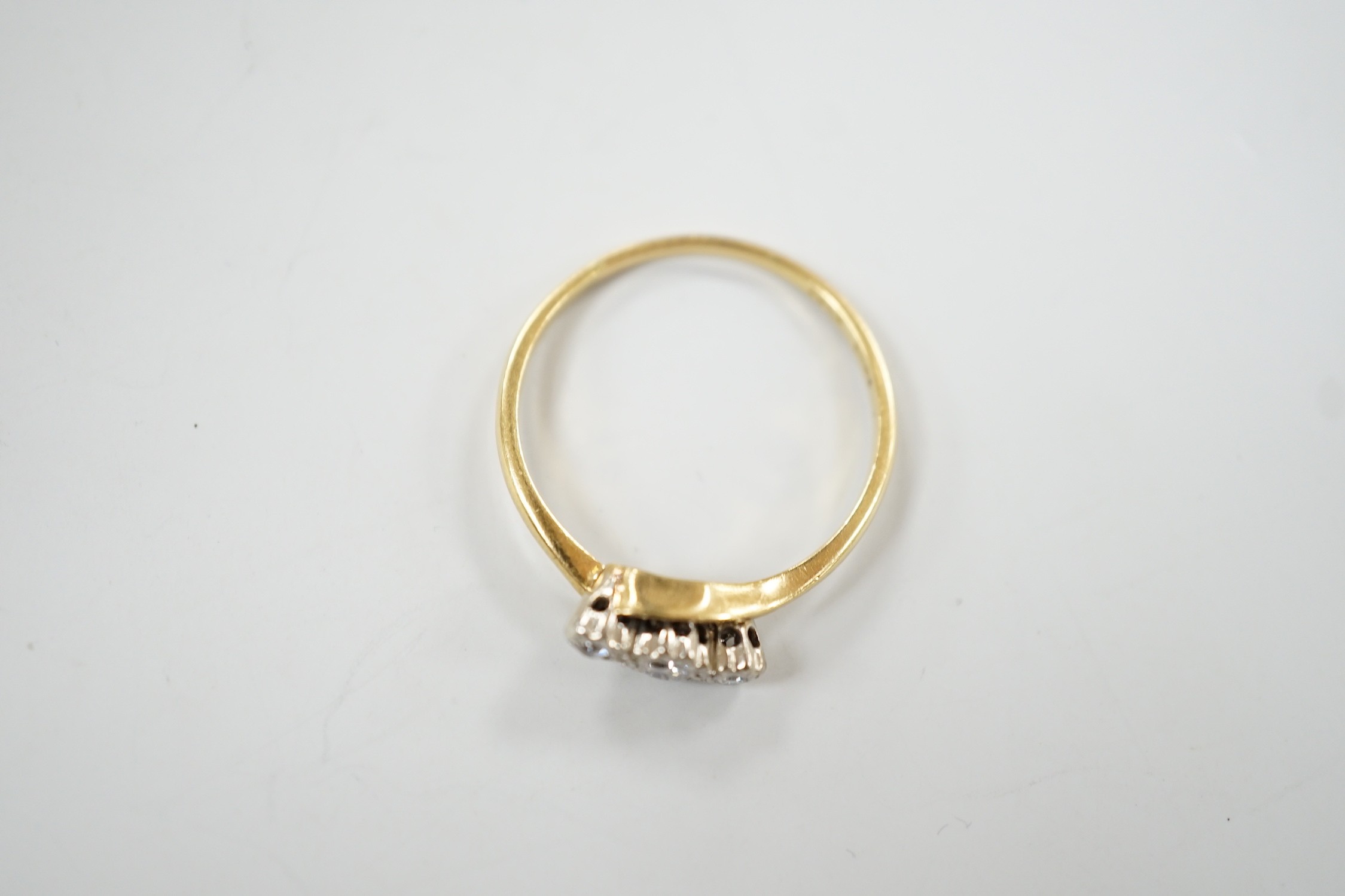 An 18ct & plat, three stone diamond set crossover ring, size T/U, gross weight 3.3 grams.